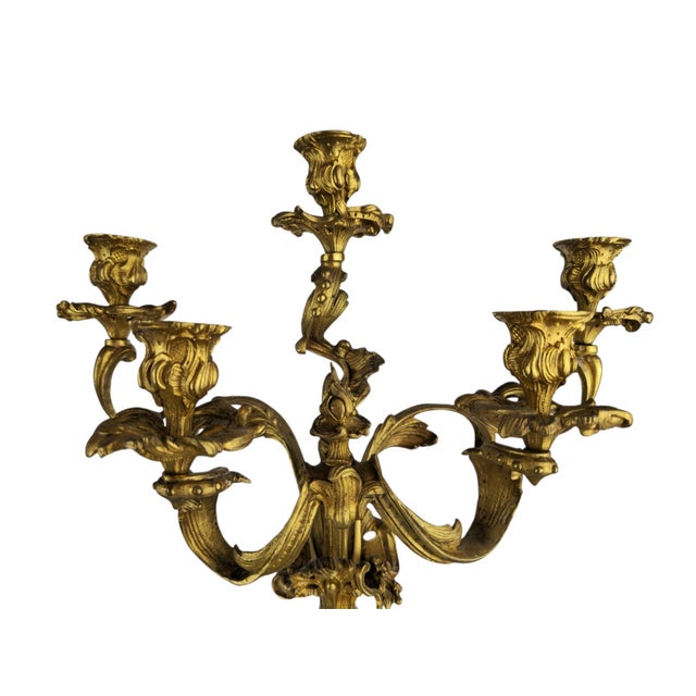 A pair of gilt bronze and brass Rococo candlesticks, each rising to five lights. The shaft of each piece is richly...