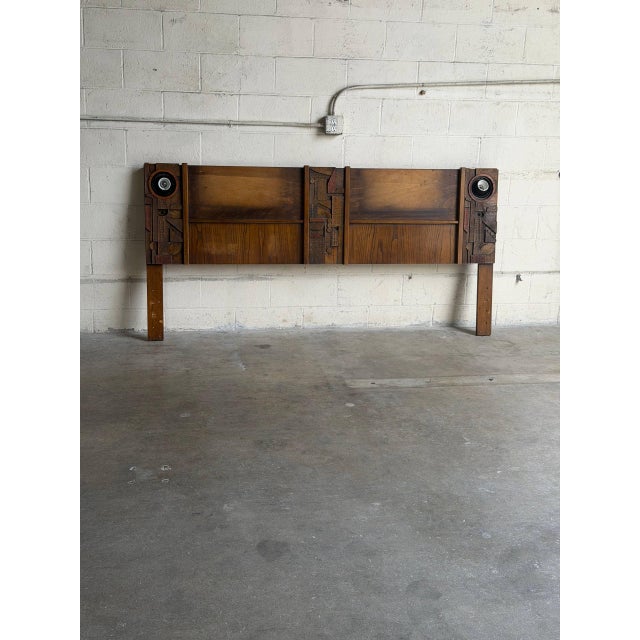 This commanding king-size bed piece showcases the bold architectural texture and geometric relief synonymous with the...