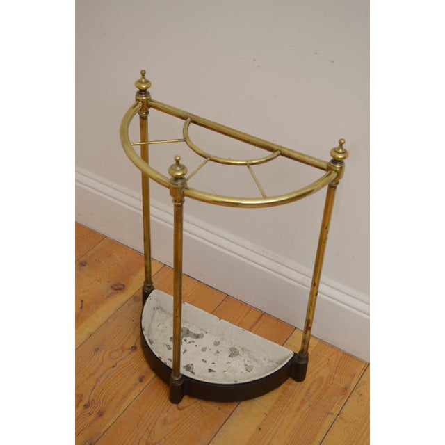 An elegant victorian brass umbrella and walking stick stand (c. 1880) featuring a classic half-moon outline accented by...