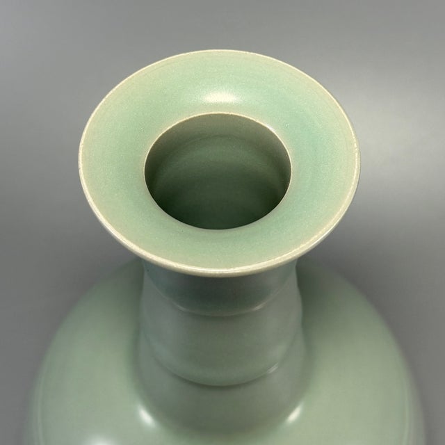 This graceful vase is crafted in classic Chinese Longquan celadon style. It features a flared rim, segmented ribbon neck...