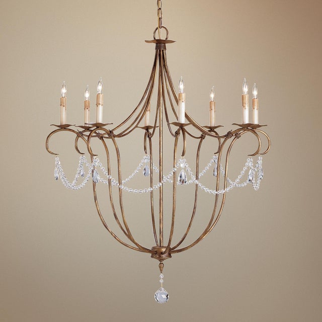 The Crystal Lights Gold Large Chandelier drips with crystal beads that swag between wrought iron curls in a gold leaf...