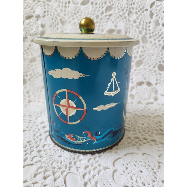 A red, white and blue nautical ship metal tin. There is some wear and rust. I think it's still darling! It looks to be...