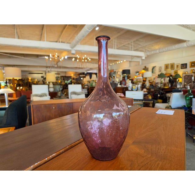 Add a touch of vintage elegance and organic warmth to your space with this striking hand-blown glass vase. Crafted in a...