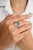 This amazing engagement ring features a creative design, highlighting a stunning emerald at its center, surrounded by...