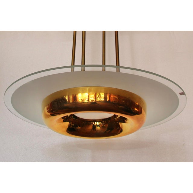 This round Art Deco chandelier, likely from the Petitot company, is made of solid brass and features a partially etched...