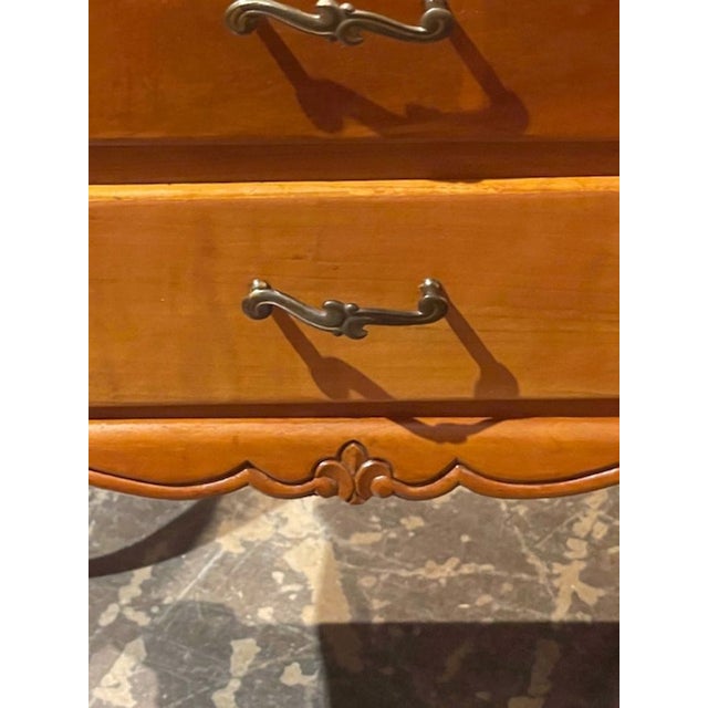 These early 20th century French Provincial fruitwood nightstands feature a medium wood tone with a gold hardware. A lovely...