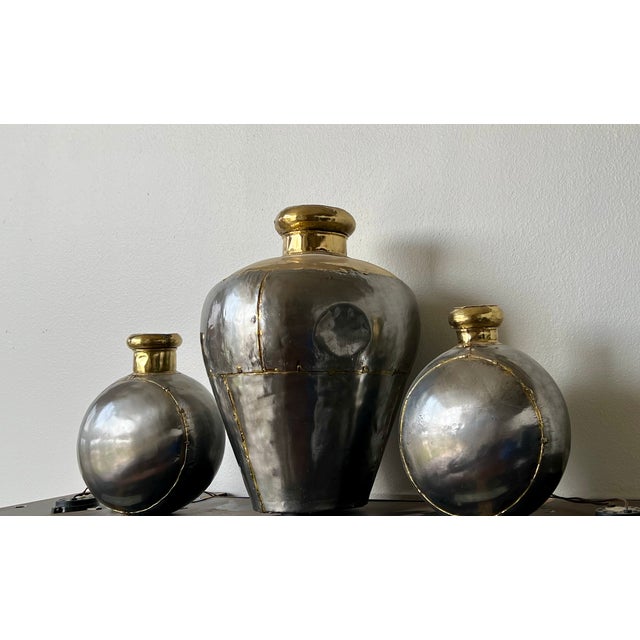 Series of three pewter metal vases with gold rims add charm to any high-end setting. These are sold as a set.