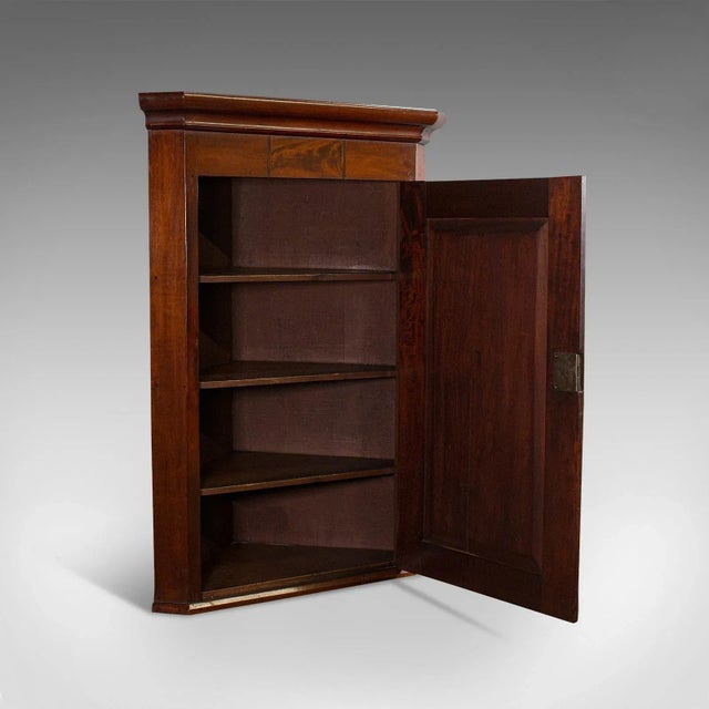 This is an antique corner cabinet. An English, mahogany and walnut cabinet with quality inlay and detail, dating to the...
