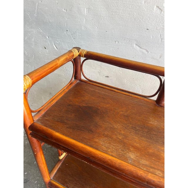 Elegant vintage shelf unit from the 1960s featuring a warm bamboo and rattan construction with beautifully curved...
