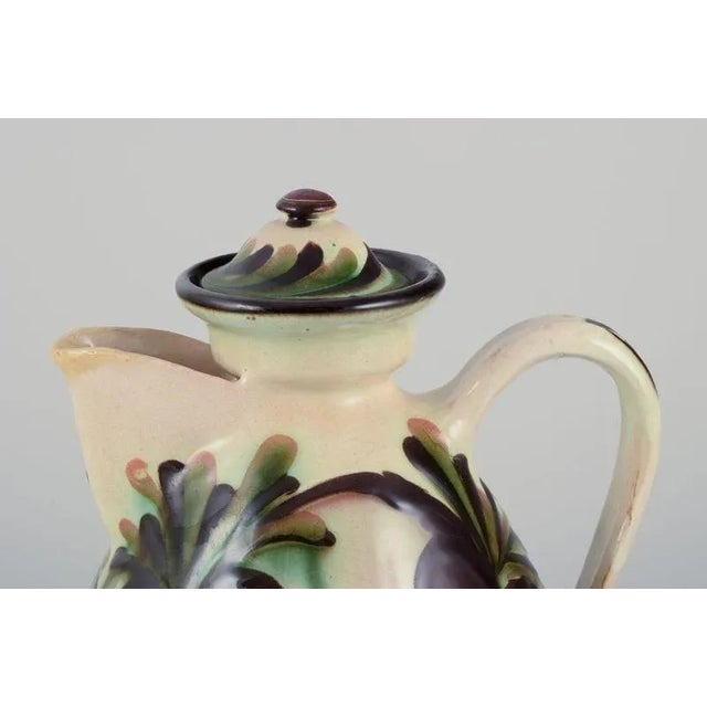 Kähler, Denmark. Chocolate jug made of ceramic decorated with polychrome glaze. Floral motifs on a cream-colored base....