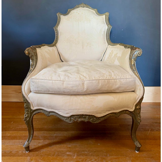 19th century gilt Louis XV Bergere chair with updated, double welted, down filled uoholstery. Ornately carved serpentine...