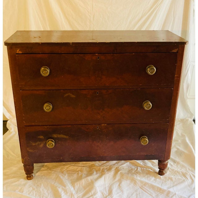 Flame Mahogany empire chest with three drawers below a curved single plank top two turned front feet