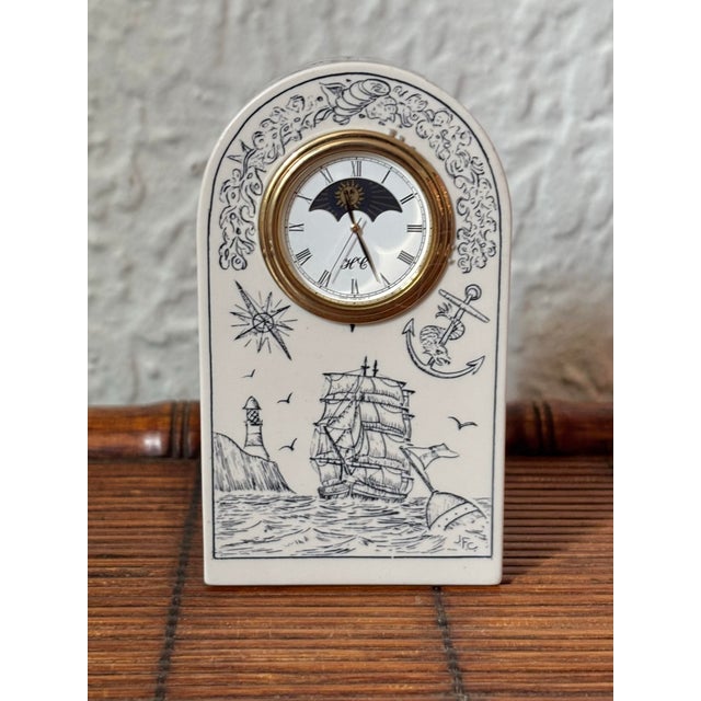 Faux 1990s scrimshaw clock with sun and moon dial. Nautical motifs include clipper ships, anchors, and compass. Sea...