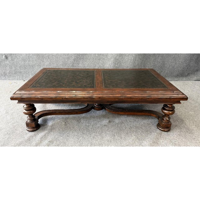 This Bernhardt coffee table features a striking decorated top with dual inset panels framed by nailhead trim, set within a...