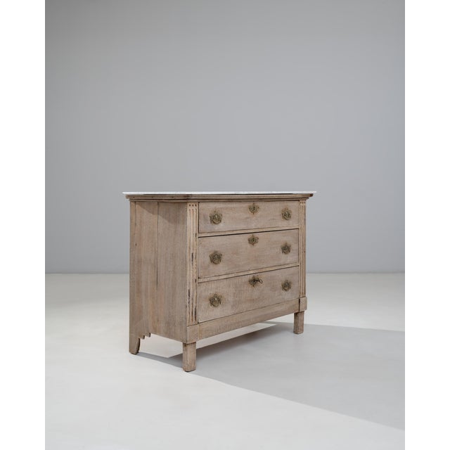 This 19th Century French Louis XVI oak chest of drawers with marble top embodies the restrained elegance and balanced...