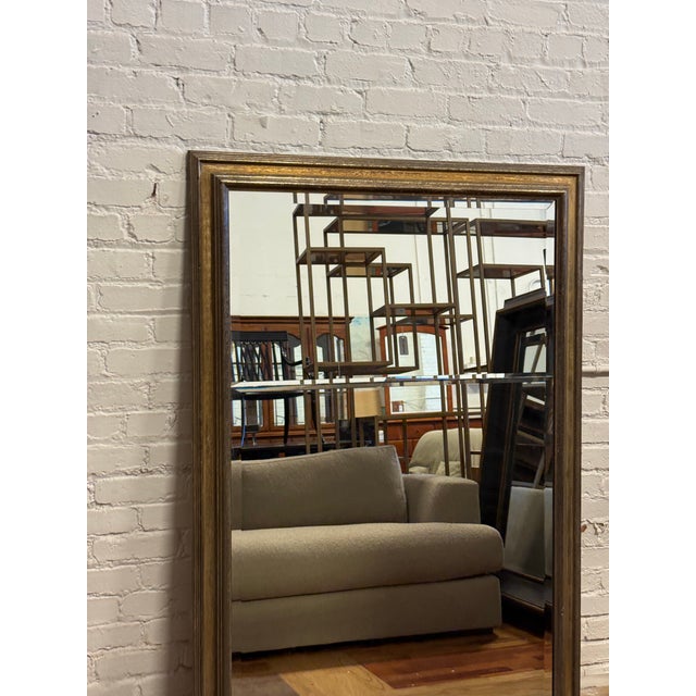Design Plus Gallery presents a Custom Full Length Mirror. A rectangular silhouette, an antiqued gilt-toned frame, and a...