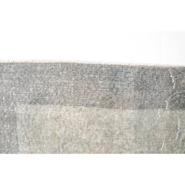This is a vintage Turkish Oushak rug from the Mid 20th Century. The piece was hand-knotted.