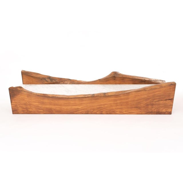Malpasso is a coffee table composed of two irregularly shaped solid olive wood planks, connected by a central slab of...