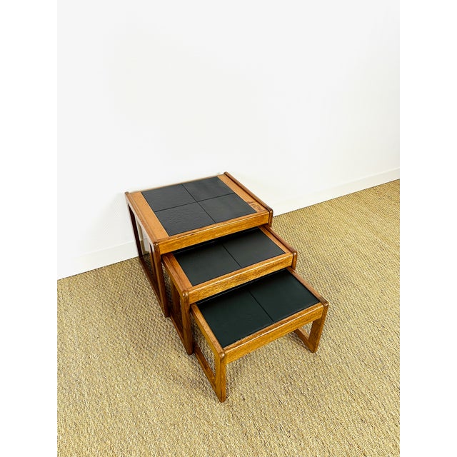An elegant set of three nesting tables in solid teak with black glazed ceramic tiles, typical of 1960s scandinavian...