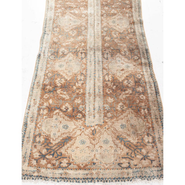 An early 20th century Indian runner fragment with a central thick camel floral band dividing the abrashed light brown...