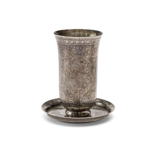 An exceptional and visually appealing Indian solid silver beaker cup and matching saucer, finely worked in niello and...