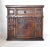 An antique Italian credenzino or small cabinet with one door and one drawer, hand-hewn and carved of heavy walnut with...