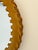 A round mirror encircled by a wide band of tan leather, entirely handcrafted, adorned with lacing and a scalloped border....