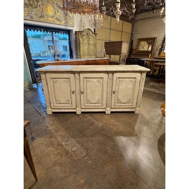 Elevate your interior with the 19th Century French Regence' Carved and Painted White Sideboard, a piece that exudes...