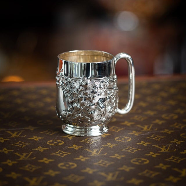 Antique 19th century victorian solid silver mug, featuring a bulbous body with detailed floral repoussé decoration with a...