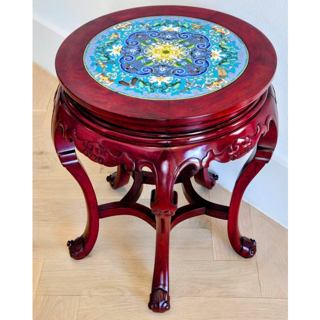 Vibrant Chinese cloisonné steals the show on this round rosewood accent table, showcasing a richly detailed floral...