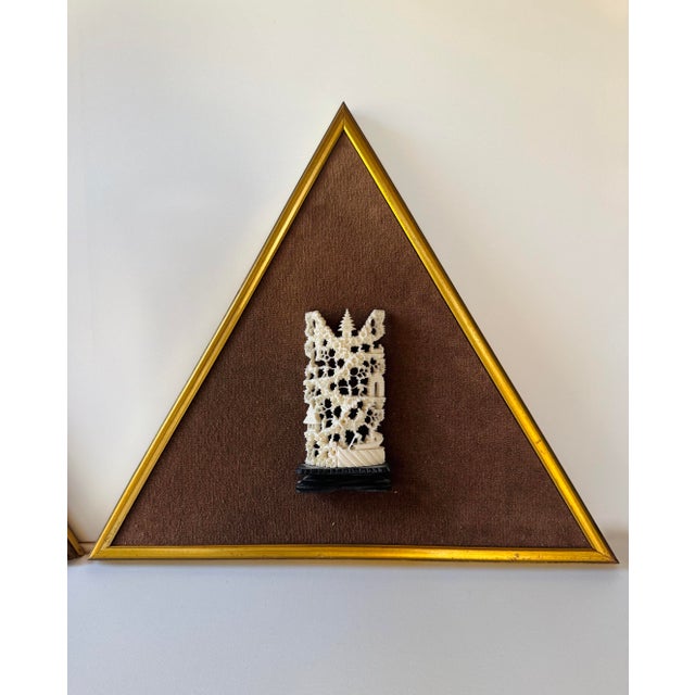 Pair of vintage hand-carved bone wall hangings presented in matching triangular gilt-tone frames with brown fabric-covered...
