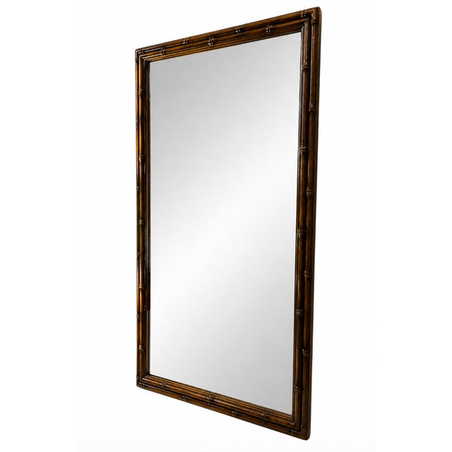 A striking vintage faux bamboo wall mirror in a rich warm brown finish, offering classic Hollywood Regency and Palm Beach...