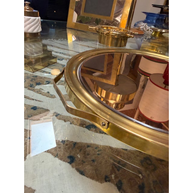 Elegant round Italian serving tray featuring a smoked mirrored surface, a polished brass frame, and sculptural side...