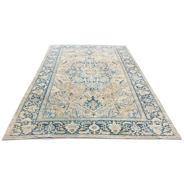 An elegant antique rug featuring a classic Heriz-inspired design in a beautifully softened palette of light beige and...