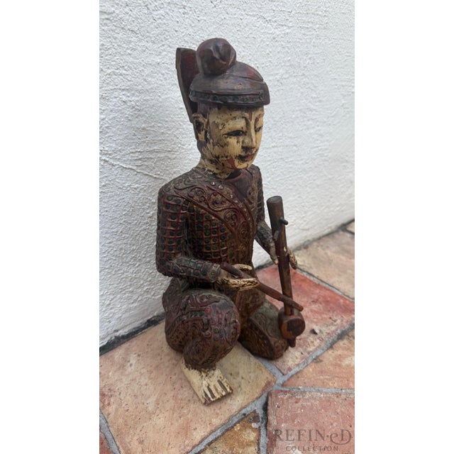 This richly detailed hand-carved Chinese wooden figural sculpture depicts a seated musician holding an unidentified...