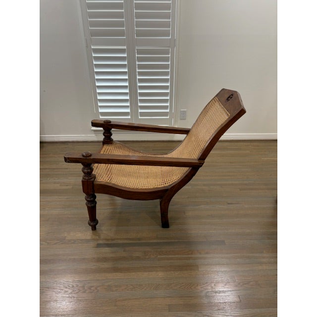This is an almost pristine British Colonial Plantation Chair with a Carved Crest and Paddle-Swing-Out Arms for Foot Rests.