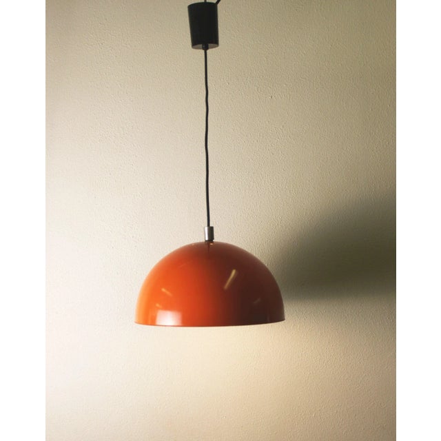 Chandelier in half-sphere of orange lacquered metal, white interior, typical of the 70s. In perfect condition. European...