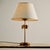 Gold-painted table lamp with textile lampshade from the 1970s. The lamp stem features organic decorations, which may be...