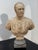 A finely detailed neoclassical marble bust depicting a Roman general in full armor, adorned with intricate reliefs of...