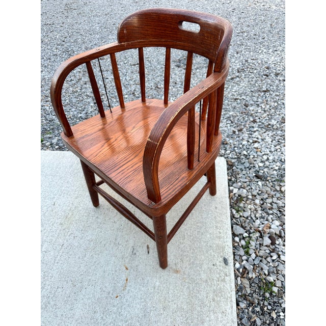 This is an antique oak captain's chair. Exceptionally sturdy, the classic Windsor style chair has a spindle back with wood...