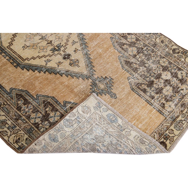Beautiful vintage Persian distressed hand-knotted wool rug with a tan color field. This piece has a beige frame and...