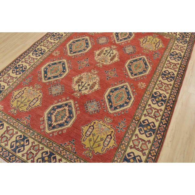 A tribal Kazak rug hand-knotted with fine wool with silk highlights on a cotton foundation. This oriental rug features...