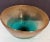 A striking hand-blown art glass bowl featuring a warm amber exterior that melts into a vivid aqua interior, creating a...