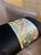 A lumbar cushion cover with a celadon satin jacquard center strip showing a red songbird perched on a gold branch,...
