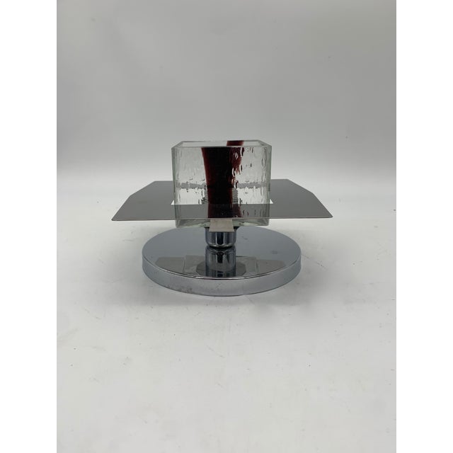 A pair of geometric wall lamps with a slightly curved square base in chromed metal, mounted on a clear glass diffuser in...