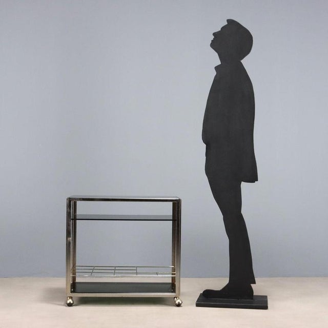 Vintage metal serving trolley, smoked glass shelves with bottle holder structure. This piece is attributed to the...