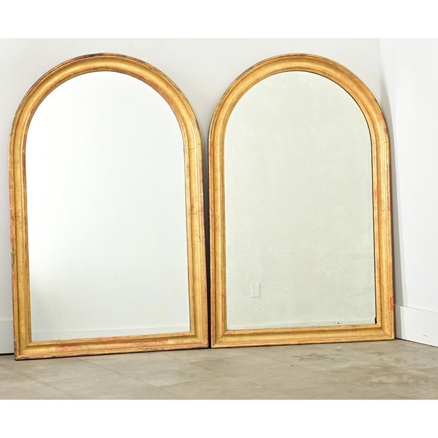 A lovely pair of gilt mirrors from 19th century France, their strong proportions are emphasized by red bole clay peeking...