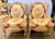 Elegant pair of French Louis XV-style wingback chairs with matching ottomans, featuring carved cabriole legs and softly...