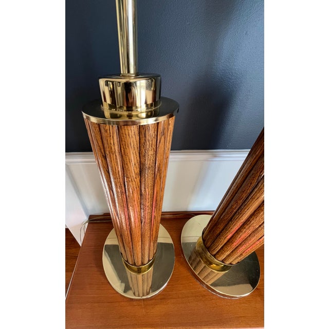 Elegant pair of vintage table lamps featuring cylindrical fluted wood bodies framed by polished brass-tone metal caps and...