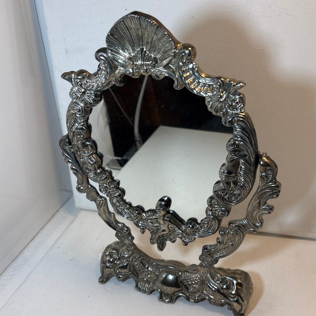 This item is a vintage Italian silver-plated tabletop vanity mirror featuring a Rococo or Baroque style with cherub...